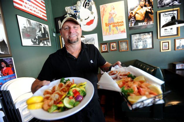 Tod Stark in the dining room holding two plates of grilled shrimp
